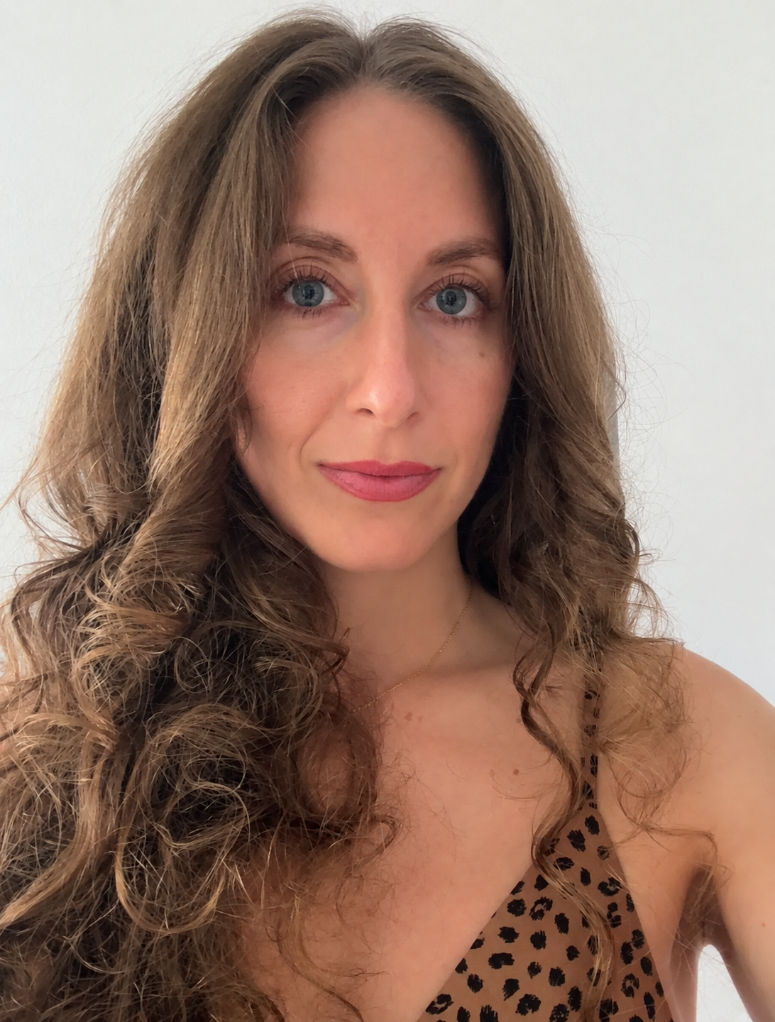 Malana Hokulani looking directly at the camera with long curly hair and a leopard-print top