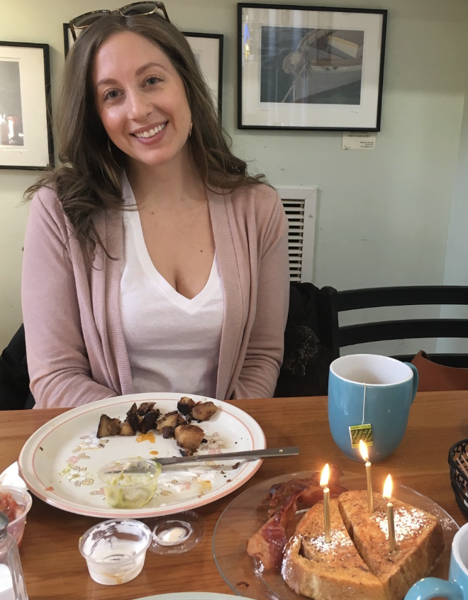 Malana smiling at her 30th birthday meal in 2018, with the birthday candles and table visible