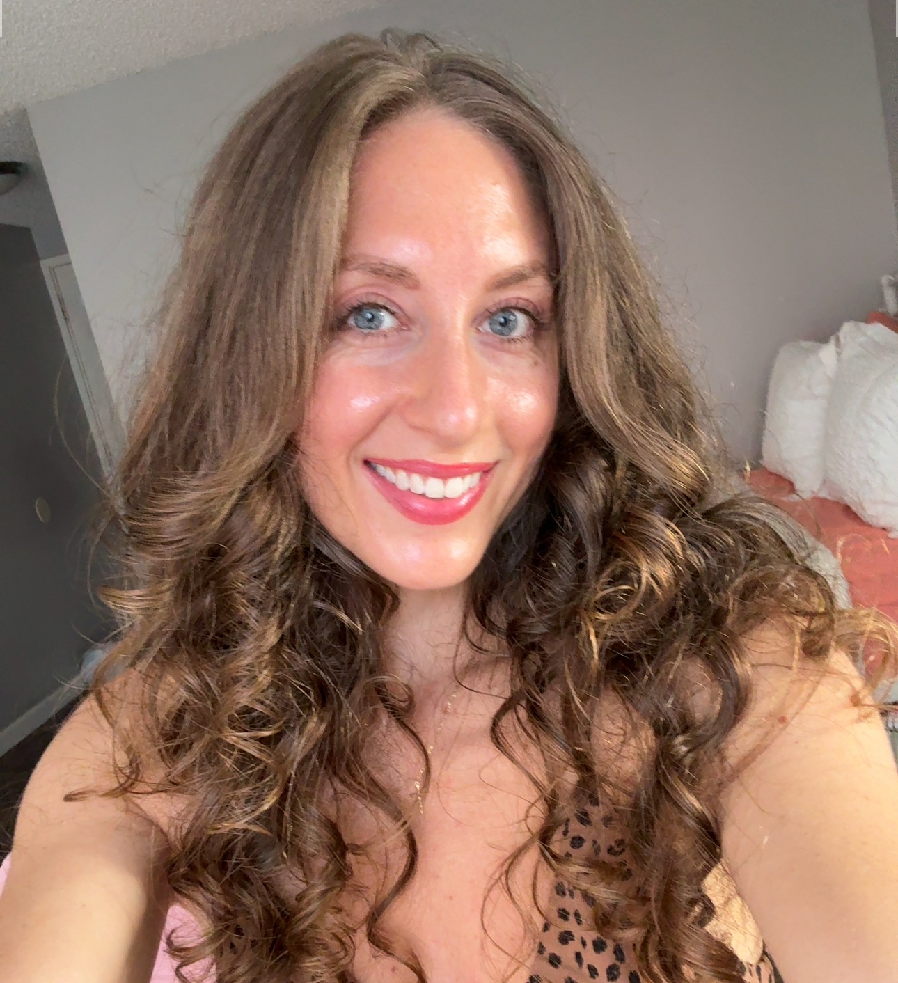Malana Hokulani smiling with long curly hair, a leopard-print top and a gold cross necklace