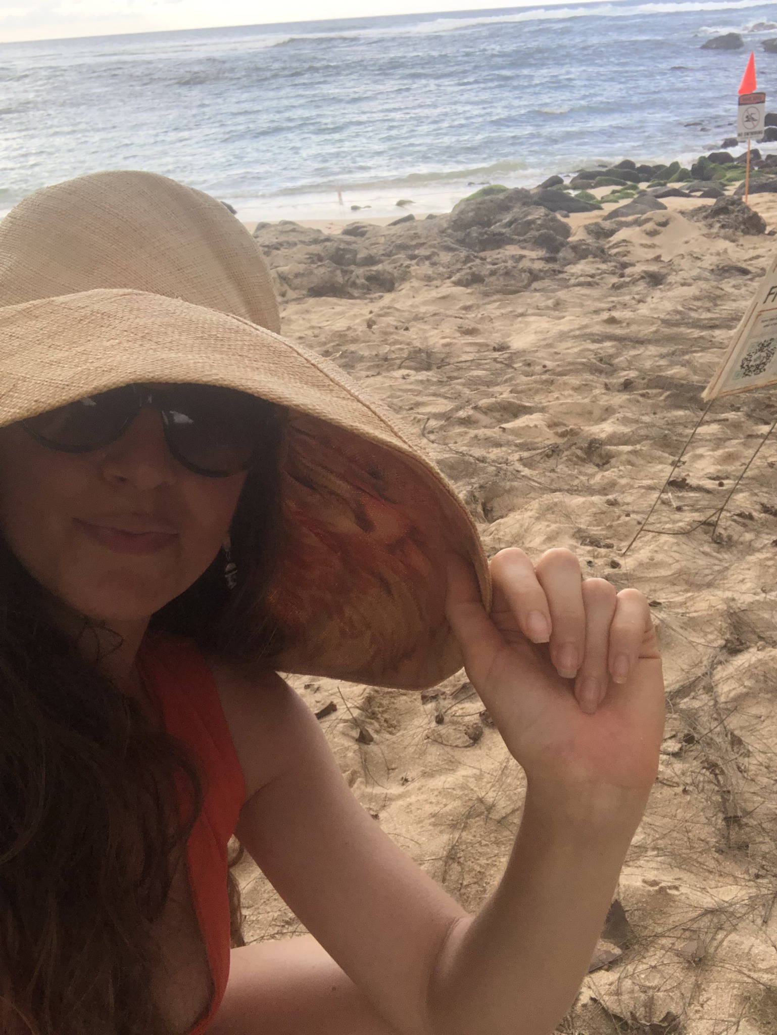 Malana wearing a sunhat by the shoreline shortly after arriving in Hawaiʻi