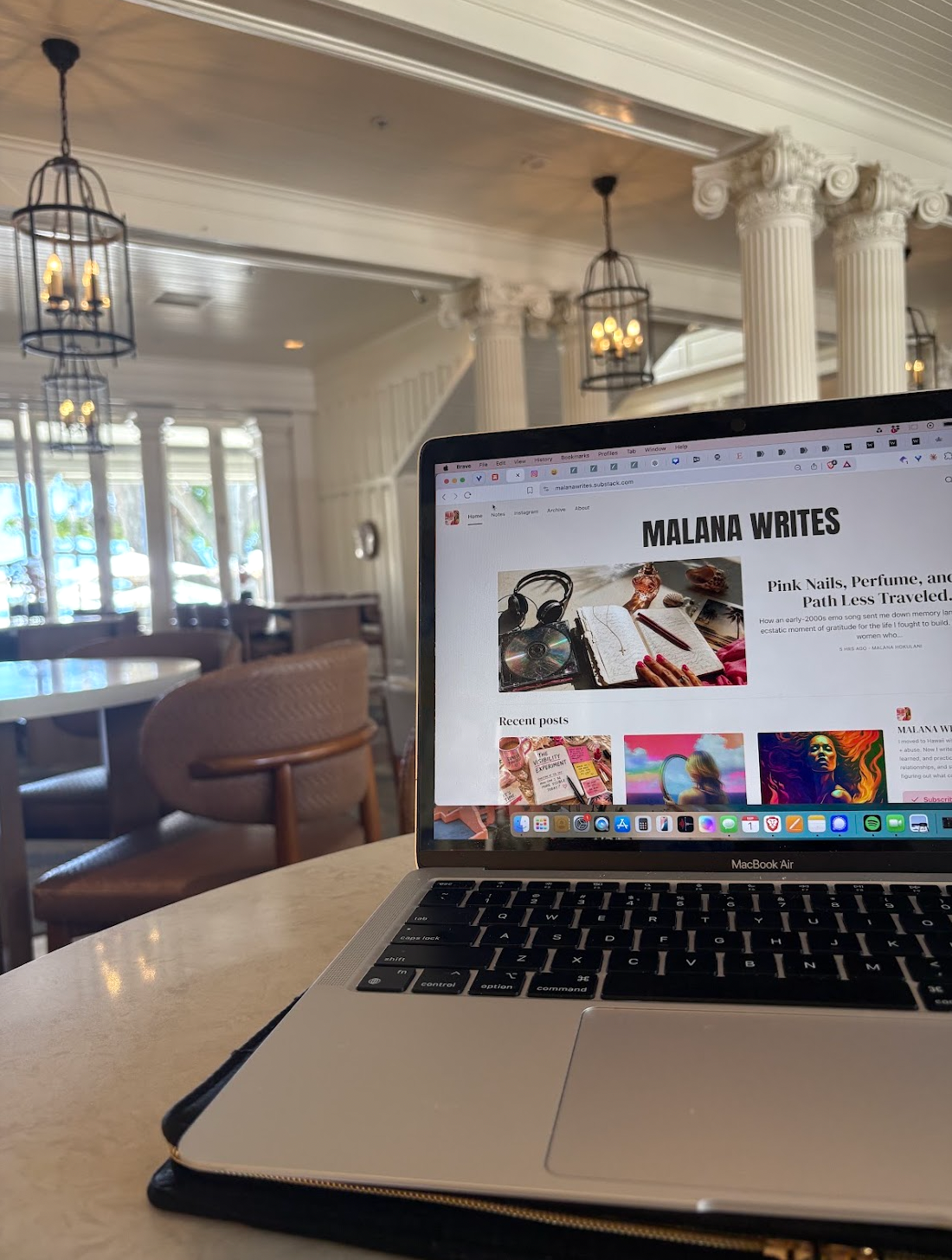 Malana Writes open on a laptop at a cafe